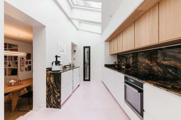 cuisine sous verrière. Linéaire de cuisine en bois clair, marbre marron et béton ciré rose