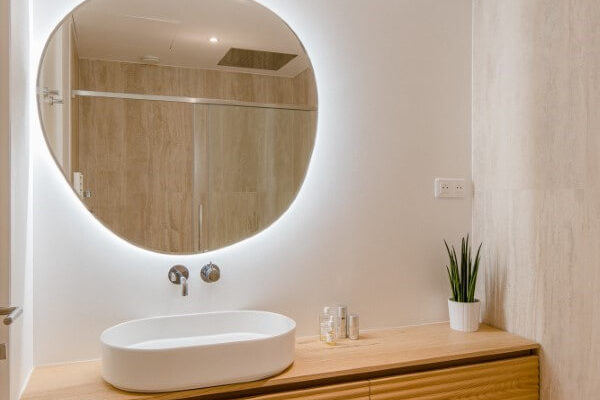 miroir rond et meuble de salle de bains cannelé en bois. Rénovation par l'agence d'architecture u design paris