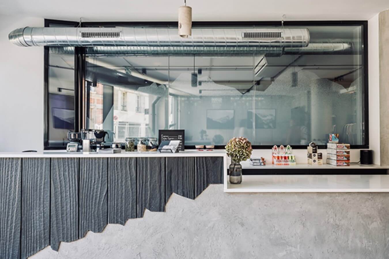 Bar en béton et bois brûlé coupé façon montagne escarpée pour le café du cycling club Storm, rénovation par l'agence d'architecture u design paris