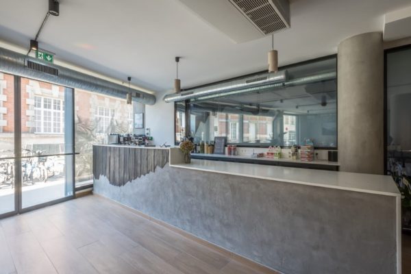 Bar en béton et bois brûlé coupé façon montagne escarpée pour le café du cycling club Storm, rénovation par l'agence d'architecture u design paris