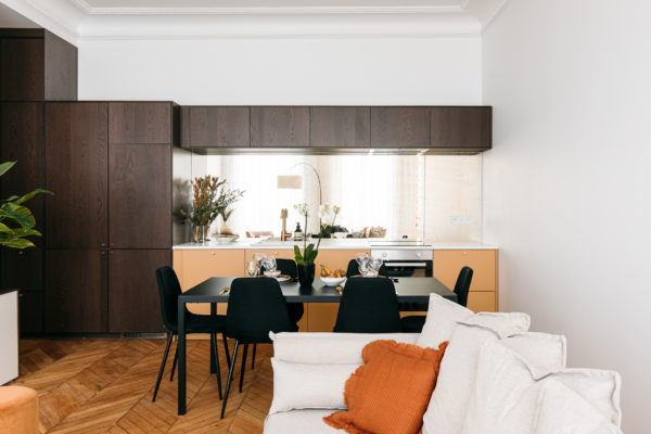 Séjour du troisième appartement. Cuisine associant bois foncé, moutarde et miroir fumé. Espace salon dans les ton beige et un parquet chevron d'origine. Rénovation après division d'un appartement en 3 locations de luxe par l'agence d'architecture U design Paris