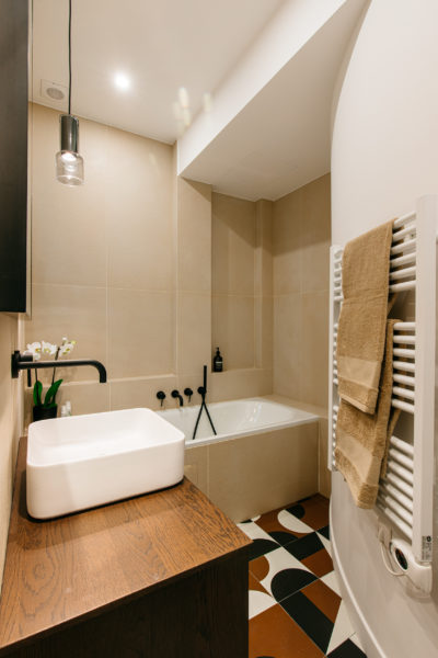 Salles de bain au miroir en arc de cercle, robinetterie noire, plan de travail en bois, carreaux effet béton ciré et carrelage Mutina. rénovation par l'agence U design paris