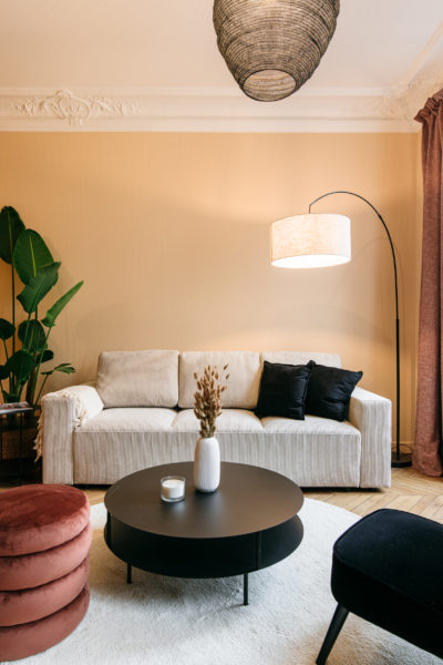 Salon couleur coquille d'oeuf, parquet point de Hondrie, table ronde et ouf terra cotta accompagnée d'un canapé en velour côtelé.